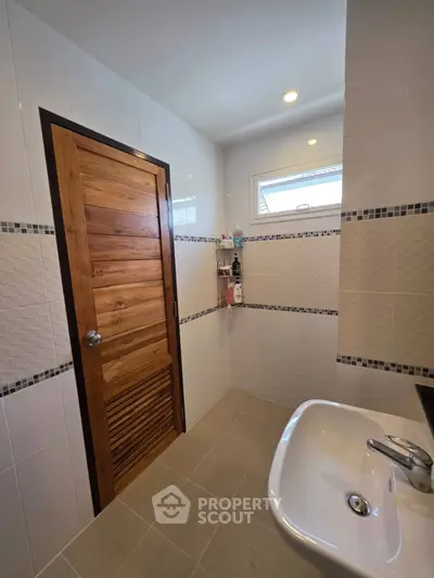 Modern bathroom with wooden door and sleek white tiles
