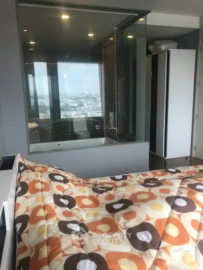 Modern bedroom with city view and glass partitioned bathtub for luxurious living.