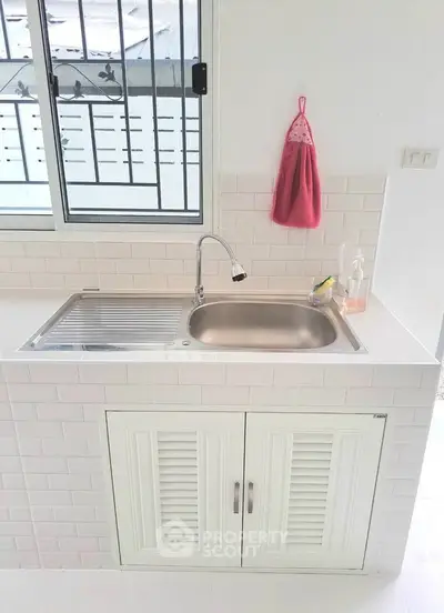 Modern kitchen sink with sleek white cabinetry and window view, perfect for contemporary homes.