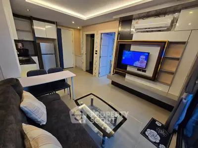 Modern living room with sleek design, featuring a wall-mounted TV, cozy seating, and integrated kitchen area.