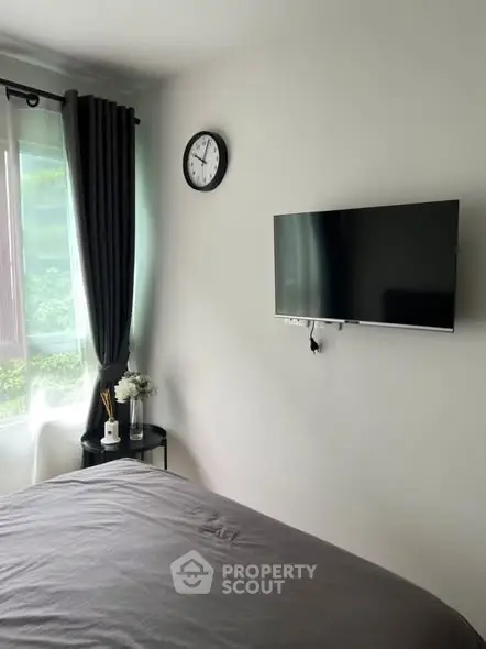 Modern bedroom with wall-mounted TV and large window with lush green view.