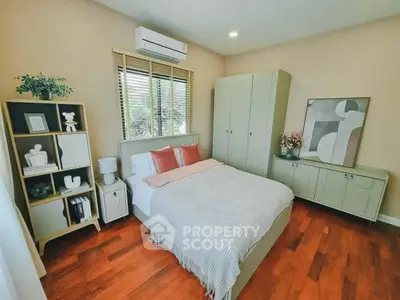Cozy bedroom with modern decor, wooden flooring, and ample natural light, perfect for relaxation.