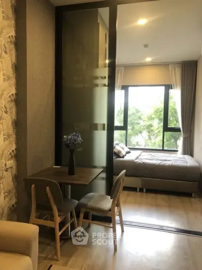 Modern studio apartment with cozy bedroom and dining area, featuring large windows and stylish decor.