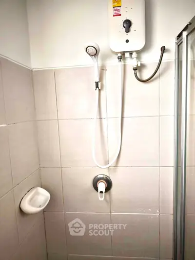 Compact bathroom shower area with water heater and tiled walls