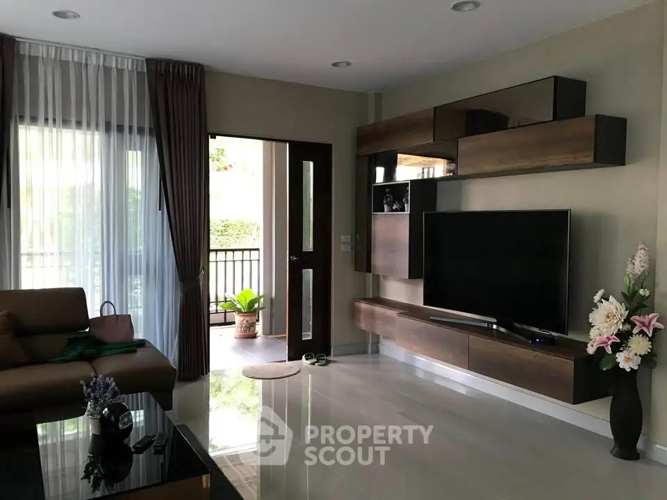 Modern living room with sleek TV unit and balcony access, featuring elegant decor and natural light.