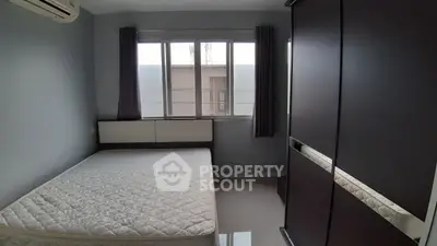 Cozy bedroom with large window and modern wardrobe in a minimalist style apartment.
