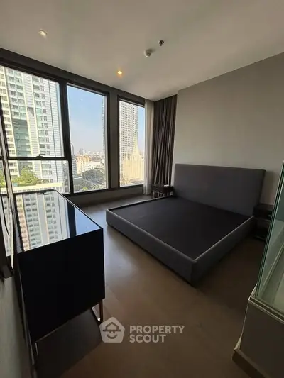 Modern bedroom with large windows offering stunning city views in a high-rise apartment.