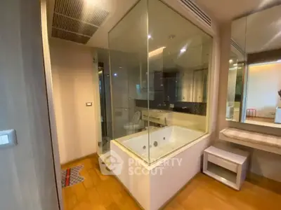 Luxurious bathroom with glass-enclosed bathtub and modern fixtures, perfect for relaxation.