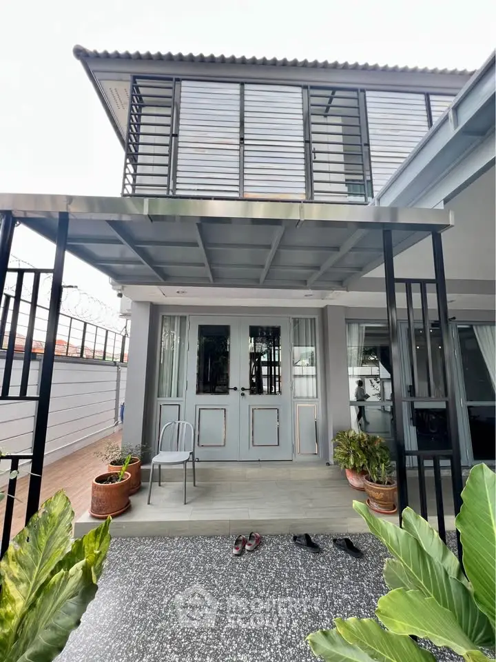 Modern two-story home with stylish exterior and inviting entrance, featuring lush plants and sleek design.
