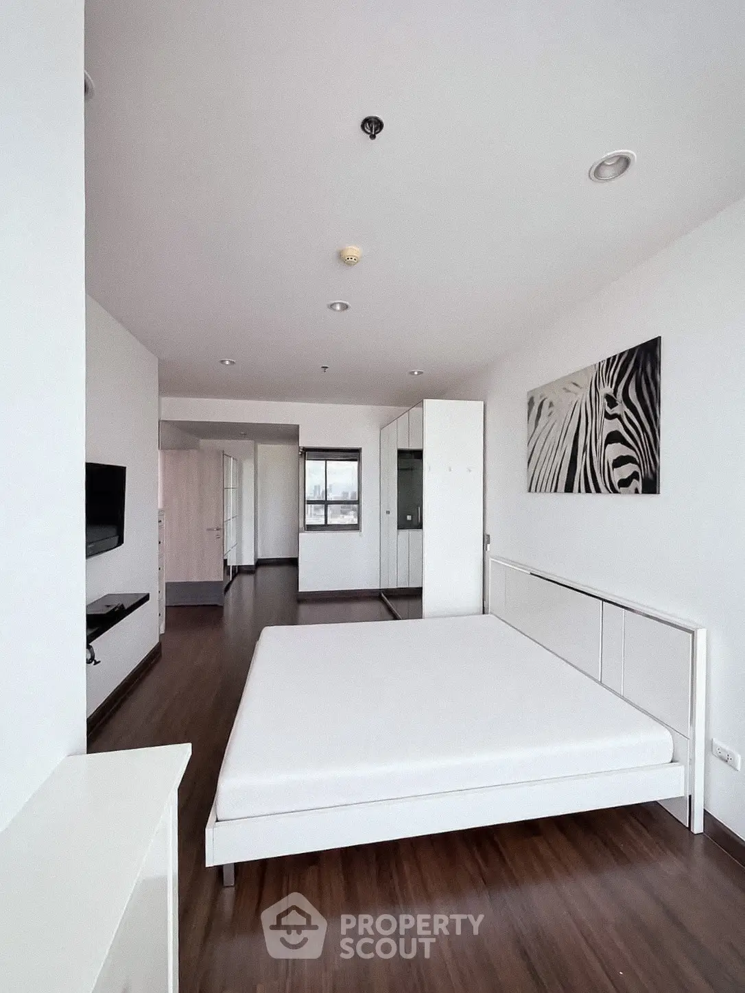 Spacious modern bedroom with minimalist decor and large window view.