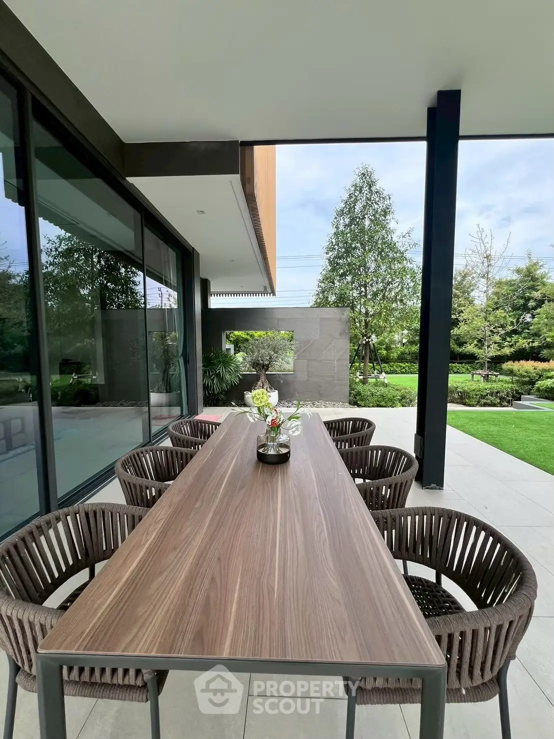 Modern outdoor patio with elegant dining set and lush garden view