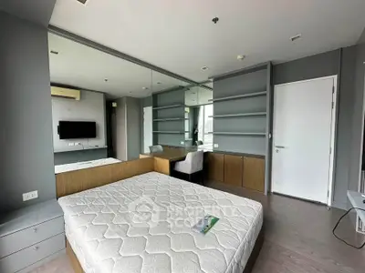 Modern bedroom with built-in shelves and large mirror, featuring a comfortable bed and sleek design.