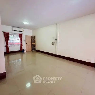 Spacious empty living room with tiled flooring and natural light, ready for customization.