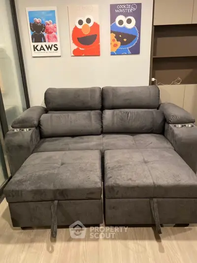 Modern living room with stylish gray sofa and playful wall art