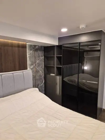 Modern bedroom with stylish headboard and mirrored wardrobe in a cozy apartment.