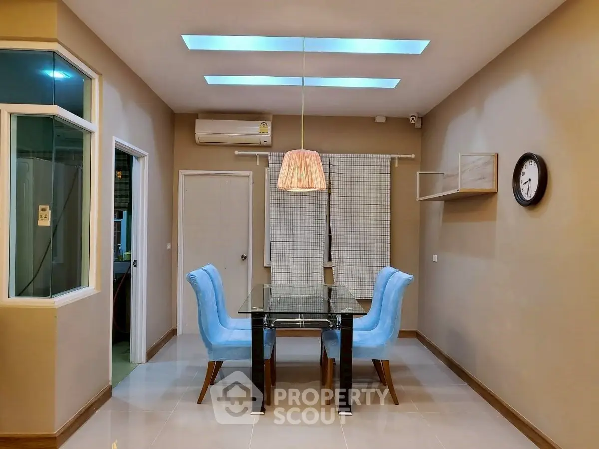Modern dining area with glass table and blue chairs under stylish lighting