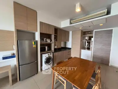 Modern kitchen with wooden cabinets, dining table, and built-in appliances in a sleek apartment.