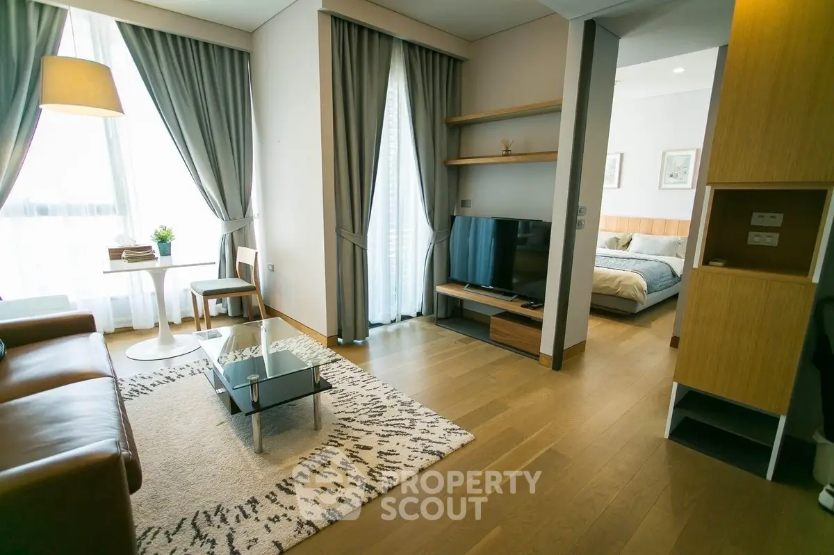 Modern living room with stylish decor and open view to bedroom, featuring elegant furniture and natural light.