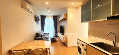 Modern living room with open kitchen, featuring sleek furniture and built-in appliances, perfect for urban living.