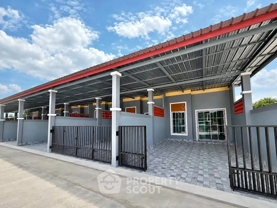 Modern single-story building with gated parking and tiled exterior under a clear blue sky.