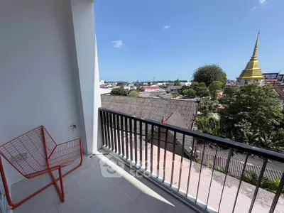 Charming balcony with scenic city view and modern red chair, perfect for relaxation.