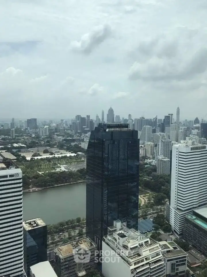 Stunning cityscape view from a high-rise building overlooking a vibrant urban skyline and lush park.