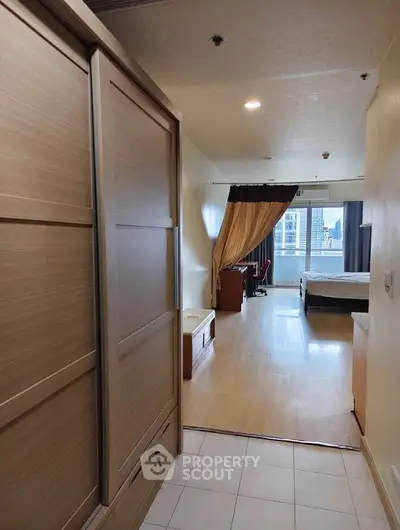 Spacious bedroom with wooden wardrobe and city view, ideal for urban living.