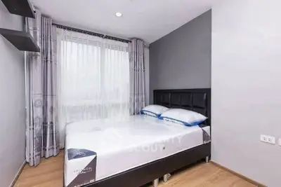 Modern bedroom with large window and stylish decor in a cozy apartment.