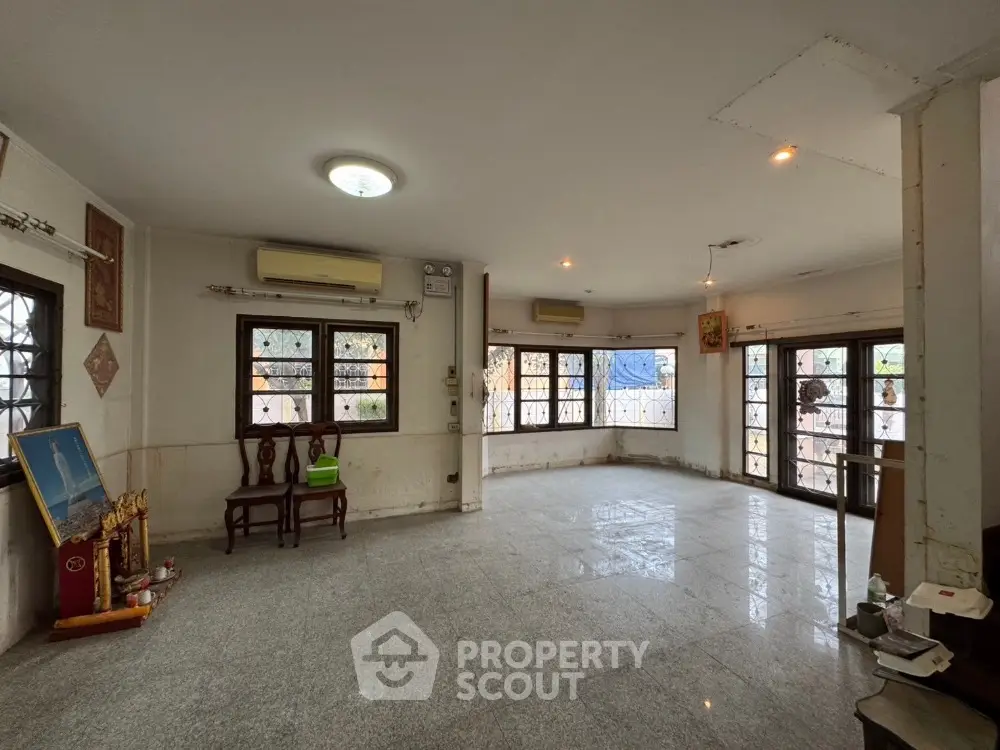 Spacious living room with large windows and marble flooring in a well-lit home.