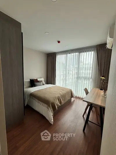 Modern bedroom with cozy decor and large window offering city view