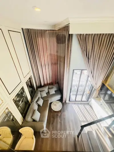 Luxurious high-ceiling living room with elegant drapes and modern furniture, offering a bright and airy ambiance.