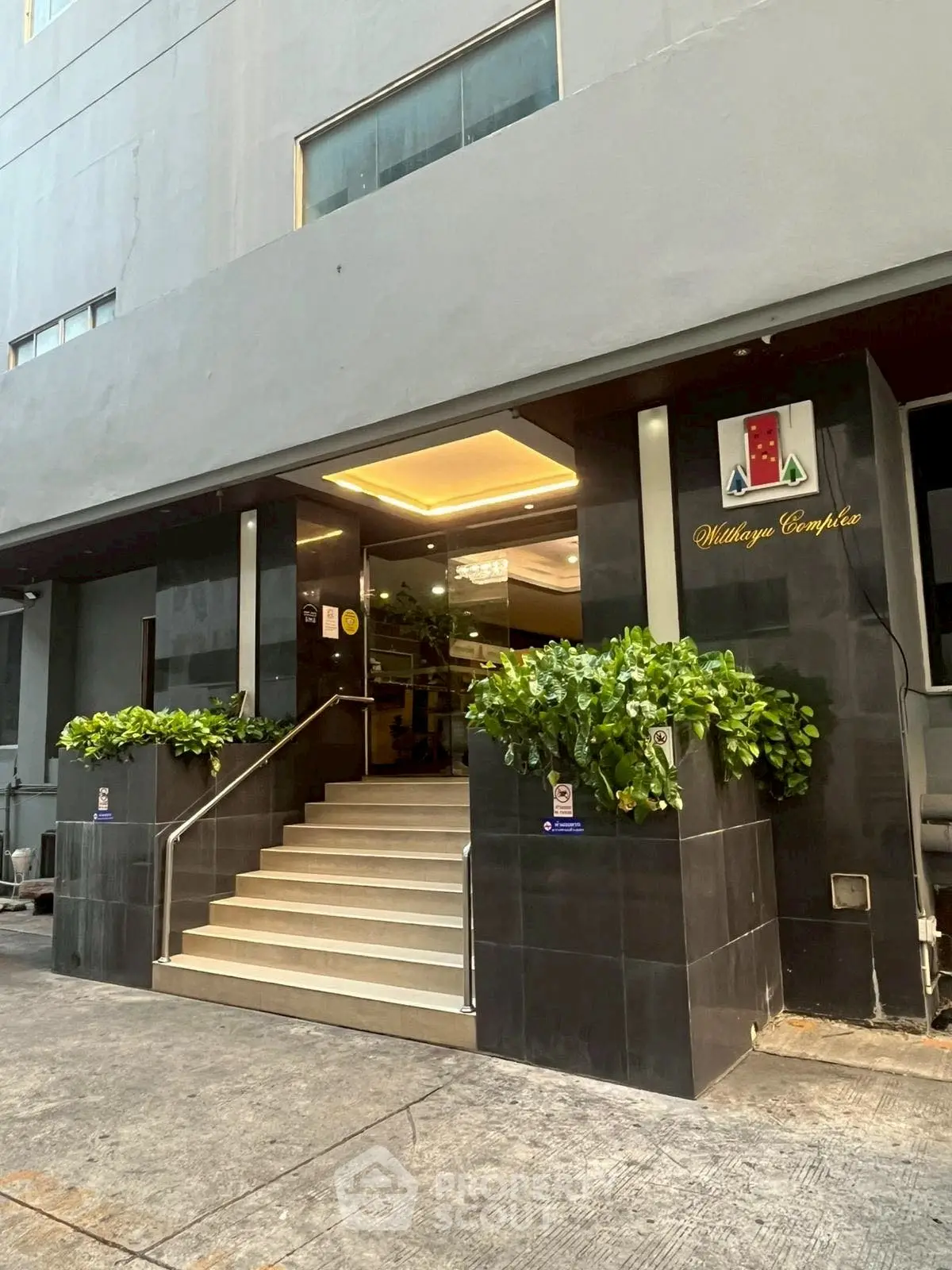 Modern building entrance with sleek design and lush greenery