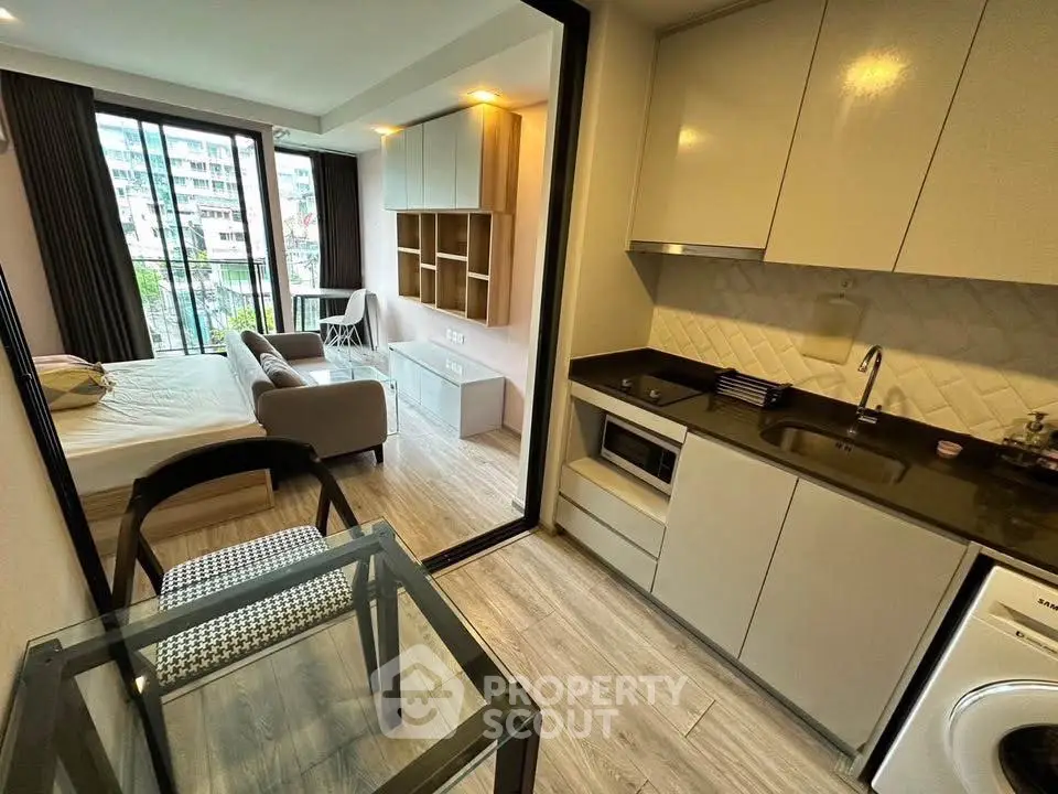 Modern studio apartment with open layout, featuring a compact kitchen and cozy living area.