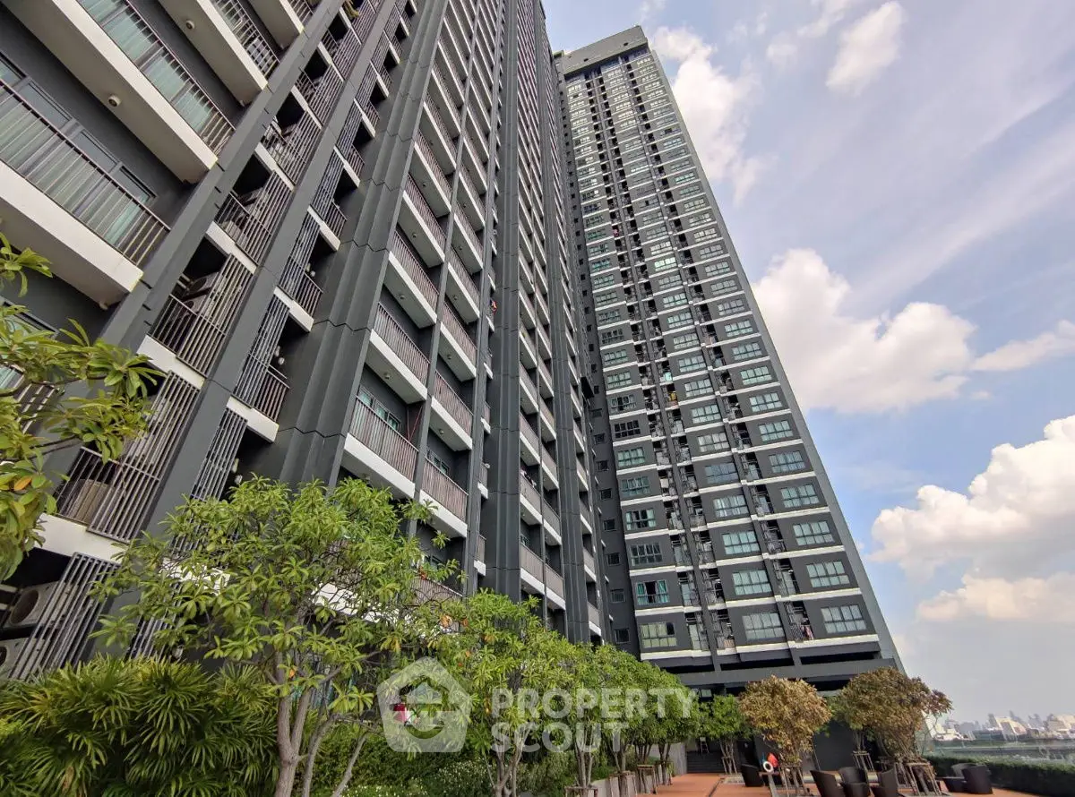 Modern high-rise residential building with lush greenery and clear blue sky.
