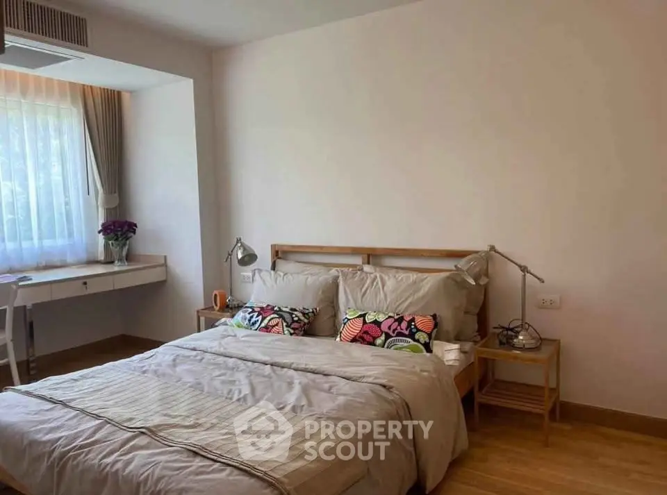 Cozy bedroom with natural light, stylish decor, and wooden flooring for a serene living experience.