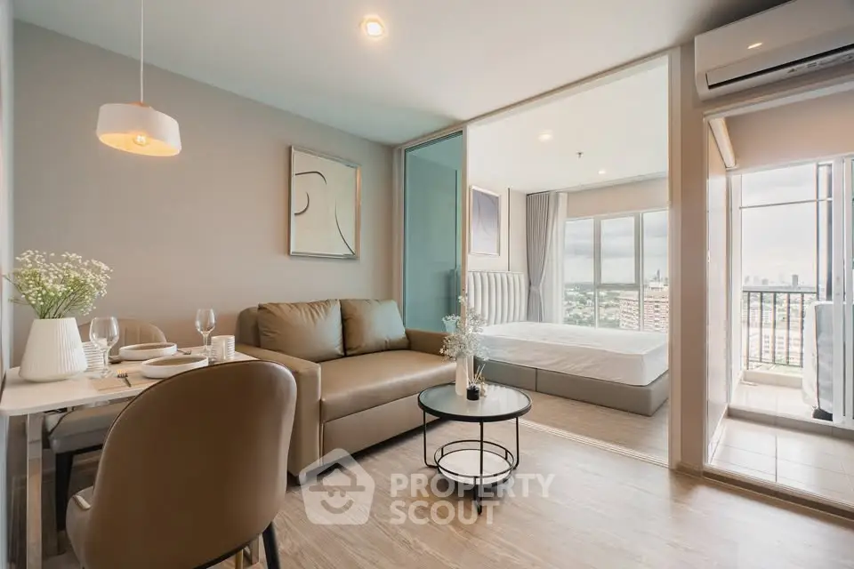 Modern open-plan living room with dining area and bedroom, featuring stylish decor and city view balcony.