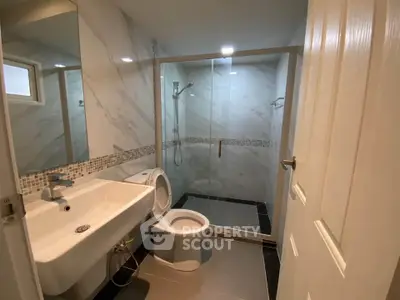 Modern bathroom with sleek design, featuring a glass shower enclosure and elegant fixtures.