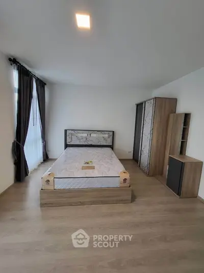 Spacious modern bedroom with elegant wooden furniture and large window for natural light.