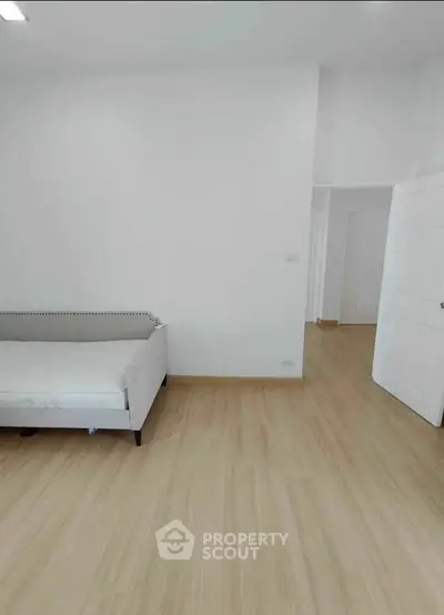 Spacious minimalist living room with light wood flooring and modern white sofa.