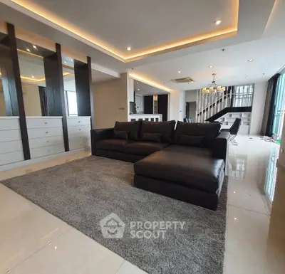 Luxurious modern living room with sleek black sofa and elegant lighting in open-concept design.