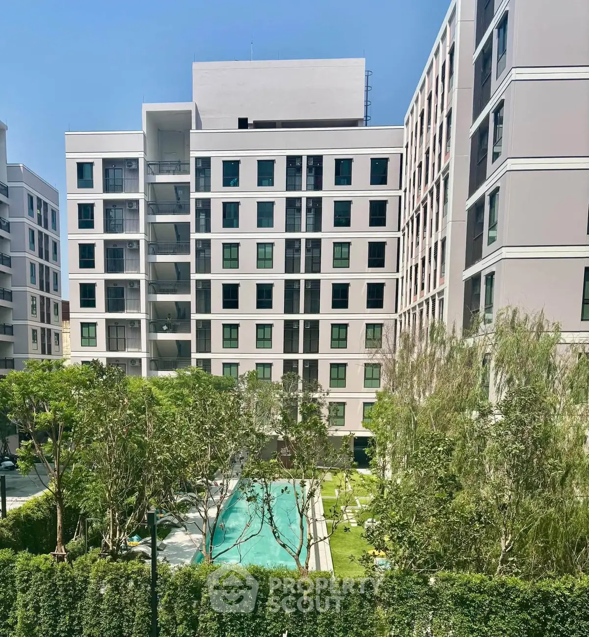 Modern apartment complex with lush garden and pool view