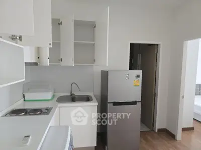 Modern kitchen with sleek white cabinets and stainless steel fridge in a compact layout.