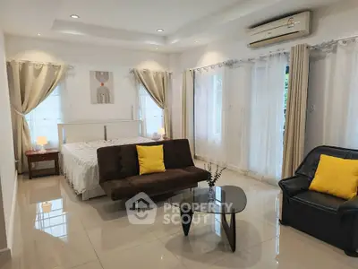 Spacious bedroom with modern decor, featuring a cozy bed, stylish seating, and ample natural light.