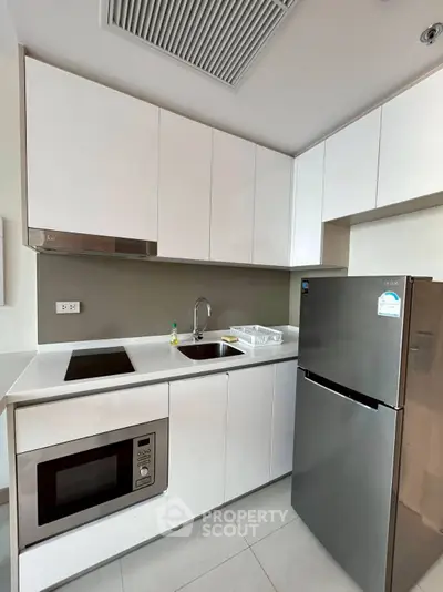 Modern kitchen with sleek white cabinets and stainless steel appliances.