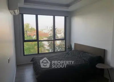 Modern bedroom with large window and city view, featuring minimalist decor and natural light.