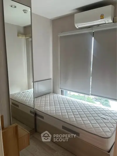 Cozy bedroom with mirrored wardrobe and air conditioning, perfect for urban living.