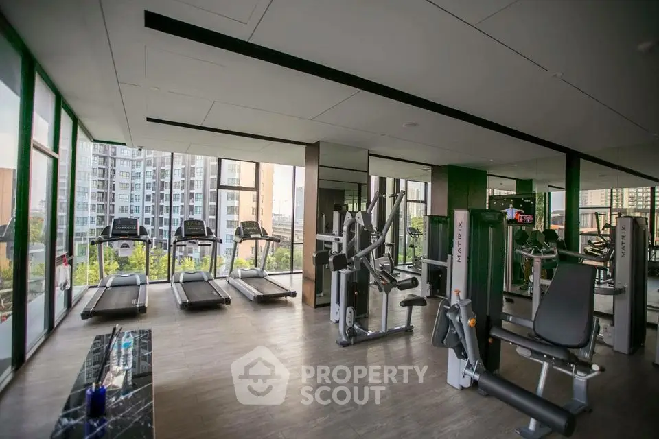 Modern gym with state-of-the-art equipment and city view in luxury apartment complex.