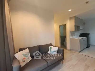 Modern living room with cozy sofa and open kitchen layout in a stylish apartment.