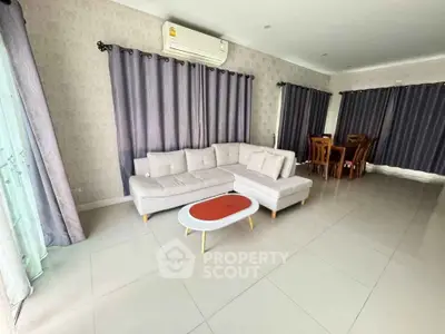 Spacious living room with modern sofa and dining area, perfect for family gatherings.