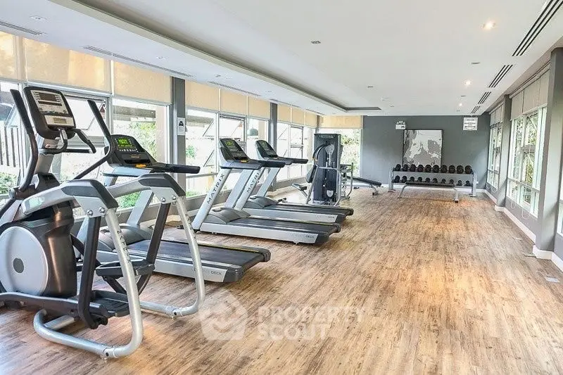 Spacious modern gym with state-of-the-art equipment and large windows for natural light.